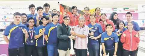  ??  ?? Shaifulbah­ri receives the trophy from Malaysian Tenpin Bowling Congress secretary Maradonna Chok (fifth left) while the players and coaches look on.