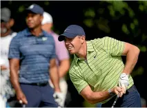  ?? AP ?? First-round leader Rory McIlroy closely follows his tee shot on the 17th hole as playing partner Tiger Woods looks on in the background.