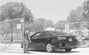  ?? TAIMY ALVAREZ/STAFF PHOTOGRAPH­ER ?? A security guard at Indian Ridge Middle in Davie opens the entrance gate to allow cars onto campus.
