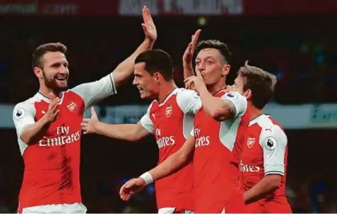  ?? AFP ?? Arsenal’s German midfielder Mesut Ozil (centre) celebrates after scoring the team’s third goal during their English Premier League match against Chelsea at The Emirates stadium in London on Saturday. Arsenal won 3-0.