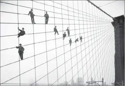  ??  ?? HANGING HIGH: In this Oct. 7, 1914, photo provided by the New York City Municipal Archives, painters are suspended from wires on the
Brooklyn Bridge in New York.