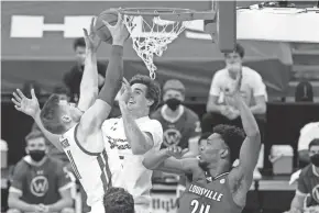  ?? ASSOCIATED PRESS ?? Wisconsin's Micah Potter (left) and Nate Reuvers reach for a defensive rebound against Louisville's Jae'Lyn Withers during the first half Saturday in Madison.