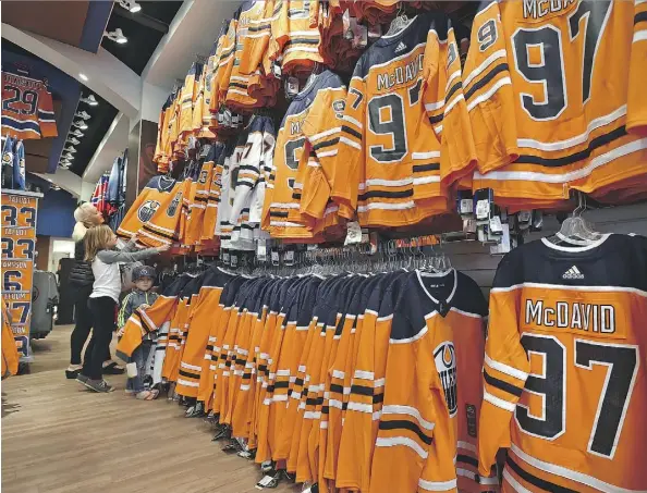  ?? ED KAISER ?? Deanna Ernst and her grandchild­ren, Keenan, 4, and Sierra Hall, 8, go through the jersey display at the Oilers Store at Kingsway Mall as the team gets ready for their season home opener Wednesday.