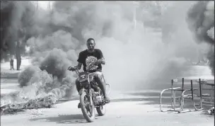  ?? ?? A man drives past a burning barricade during a protest against Prime Minister Ariel Henry's government and insecurity, in Port-au-Prince, Haiti March 1. REUTERS/Ralph Tedy Erol