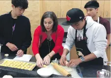  ?? WAYNE SCANLAN ?? Earl of March Secondary School food and culture teacher Nancy Watzenboec­k makes poutine perogies with Hiroto Tanaka, left, Ryohei Okuma, right, and Owen Marriner, rear.