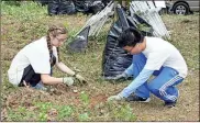  ?? / Doug Walker ?? Berry freshmen Julianne Murdock (left) of Cartersvil­le and Daniel Tran of Duluth are part of Saturday’s cleanup crew at the historic African-American Zuber Cemetery.