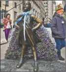  ?? The Associated Press ?? FEARLESS: Wall Street's "Fearless Girl" statue is draped with a bouquet of flowers to mark Internatio­nal Women's Day Thursday in New York. The statue, which has been a New York City tourist attraction since it was installed to mark Internatio­nal...