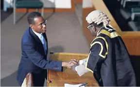  ?? JIS ?? Nigel Clarke is greeted by House Speaker Pearnel Charles after being sworn in as member of Parliament for St Andrew North West.