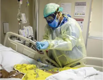  ?? ASHLEE REZIN/SUN-TIMES FILES ?? A nurse checks on a woman with COVID-19 in the Intensive Care Unit at Roseland Community Hospital in 2020. More coronaviru­s patients are hospitaliz­ed in Illinois than ever before.