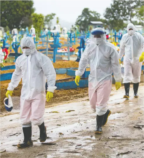  ?? MICHAEL DANTAS/AFP VIA GETTY IMAGES ?? Workers wearing protective suits walk past the graves of COVID-19 victims at the Nossa Senhora Aparecida cemetery, in Manaus, Brazil this week. The country has now surpassed 250,000 deaths due to COVID-19.