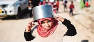  ??  ?? KHAZIR REGION: A displaced Iraqi girl from Mosul walks holding an empty pot after the food finished at a refugee camp in the Khazir region between Arbil and Mosul. — AFP