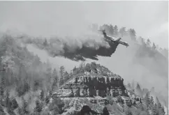  ?? Associated Press ?? ■ An aircraft makes a fire retardant drop on a wildfire in the mountains and forests near Durango, Colo.