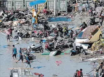  ?? TATAN SYUFLANA THE ASSOCIATED PRESS ?? People survey damage at a shopping mall Sunday after an earthquake and a tsunami in Palu. President Joko Widodo says authoritie­s are deploying more heavy machinery so workers can recover more victims Monday.