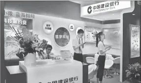  ?? PROVIDED TO CHINA DAILY ?? CCB employees work at the company’s booth during a financial products exhibition in Shanghai.