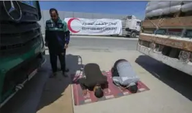  ?? Amr Nabil/Associated Press ?? Egyptian drivers of humanitari­an aid perform noon prayers Saturday as they wait to cross the Rafah border crossing between Egypt and the Gaza Strip.