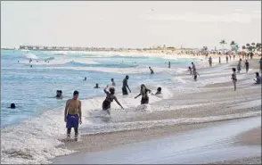  ?? Wilfredo Lee / Associated Press ?? Beachgoers play in the waves on Miami Beach's famed South Beach on Monday. A curfew is in effect that could extend until the end of spring break.