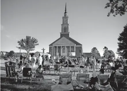  ?? [SARAH PHIPPS/ THE OKLAHOMAN] ?? Friends and family of Oklahoma Baptist University graduates watch an outdoor graduation ceremony Aug. 1 on the south lawn of Raley Chapel on the OBU campus in Shawnee.