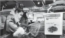  ?? NIU JING / FOR CHINA DAILY ?? A customer picks crawfish from a tank at a market in Wuhan, capital of Hubei province, on April 1.