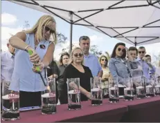  ?? AP PHOTO/WILFREDO LEE ?? Annika Dworet (left) mother of shooting victim Nicholas Dworet, lights a candle for him, on Tuesday at a ceremony in Coral Springs, Fla., honoring the lives of the 17 students and staff of Marjory Stoneman Douglas High School that were killed on Valentine’s Day, 2018.