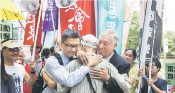  ??  ?? Activists Chan Kin Man (centre left) and Chu Yiu-ming (centre right) hug a supporter (centre) in front of the District Court before the trial on public nuisance charges of some of the leaders of the 2014 ‘Umbrella Movement’ rallies. — AFP photo