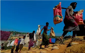  ?? — AFP ?? Rohingya Muslim refugees carry brick to make road at Kutupalong refugee camp in Bangladesh’s Ukhia district