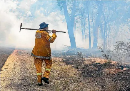  ?? FAIRFAX ?? A firefighte­r inspects a fire ground at Deepwater, near Bundaberg, Australia.