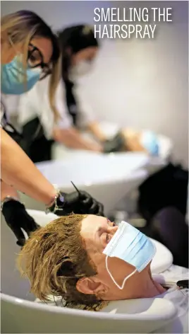  ?? Picture: Reuters ?? Women wear protective masks in a hair salon, as Italy eases some lockdown measures put in place during the coronaviru­s outbreak, in Milan, Italy, yesterday.