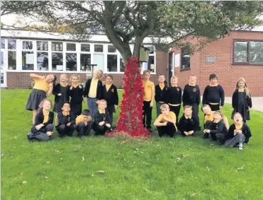  ??  ?? WISE Owls at a rural school have created a poppy tree.Pupils in theWise Owls class at Blackshaw Moor C of E First School have designed the poppy tree in preparatio­n for learning about the centenary of the end of WWI next half term.The children have collected and painted plastic bottle tops to create the poppies.Class teacher Claire Worrall said that parents and visitors to the school had commented on how lovely the poppy tree looked.Pictured are pupils around the poppy tree.