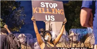  ?? APU GOMES/AFP ?? MAKIN RUSUH: Foto atas, seorang demonstran membawa poster di depan barikade polisi di kawasan Gedung Putih kemarin WIB. Di Los Angeles, polisi mulai kewalahan menghadapi pengunjuk rasa. Sebuah mobil polisi menjadi sasaran amukan massa.