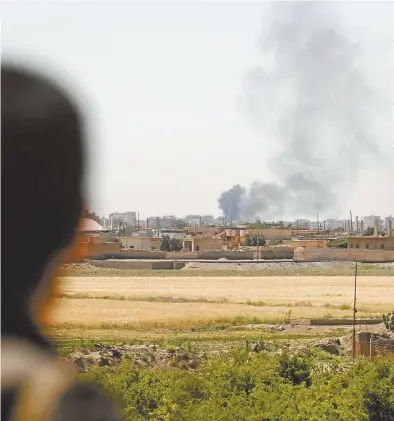  ??  ?? A member of the Syrian Democratic Forces watches as smoke rises from al-Raqqa this month.