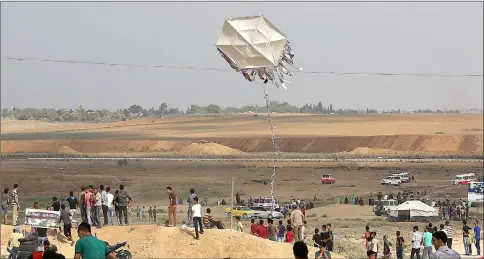  ??  ?? Palestinia­ns fly a kite near the Gaza border with Israel (background), east of Jabalia. — AFP photo