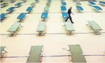  ?? Christian Murdock, The Gazette ?? Jason Horn, of the Springs Rescue Mission, sets up cots in the City Auditorium on Wednesday as the Colorado Springs shelter sets up an isolation shelter for homeless people with symptoms of the COVID-19 virus, or who are discharged from hospitals after having been treated for it. The shelter, which opened Wednesday night, will hold up to 100 people.