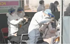  ?? — AFP photo ?? Medical workers wearing protective gear take a nasal swab sample from visitors at a Covid-19 coronaviru­s testing centre in Seoul.