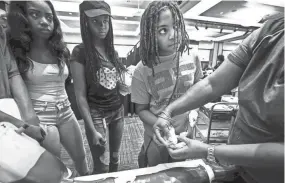  ??  ?? McKaylah Jackson, right, learns to draw blood during the C2 Institute Showcase (College, Career & Technology Education) at the University Center on the University of Memphis campus. The C2 Institute provided education and hands-on experience with jobs...