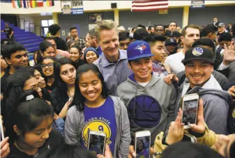  ?? Michael Short / Special to The Chronicle ?? Golden State Warriors head coach Steve Kerr (center) takes photos with students at Newark Memorial High School following a town hall meeting on curbing gun violence.