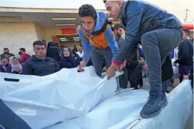  ?? AP PHOTO/ADEL HANA ?? On Sunday, Palestinia­ns load the bodies of their relatives killed in the Israeli bombardmen­t of the Gaza Strip onto a truck in Deir al Balah, Gaza Strip.