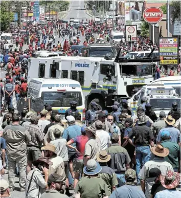  ?? Picture: REUTERS/SIPHIWE SIBEKO ?? BARRIER: Police officers stand between members of the farming community and the Economic Freedom Fighters ahead of the court appearance of two suspects for the murder of a farm manager, Brendin Horner, in Senekal, in the Free State on Friday.