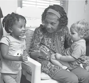  ?? SCOTT HECKEL/CANTON REPOSITORY ?? Saundra Turpin holds Micah Yeager, right, and speaks with Anita Robinson, 3, left, on Wednesday at Mi Amore’s House, the daycare center Turpin operates in Plain Township. Turpin, 69, is graduating from college Sunday with a degree in early childhood education.