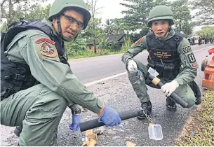  ??  ?? LEFT Bomb squad officers collect evidence on a road where a number of pipe bombs were found after the attack on the security checkpoint.