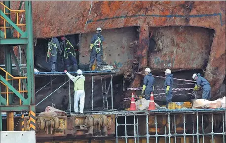  ?? LEE SANG-HACK / YONHAP VIA ASSOCIATED PRESS ?? Workers search for bone fragments from the wreckage of the salvaged ferry at a port in Mokpo, South Korea, on Wednesday.