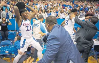  ??  ?? Kansas’ Silvio De Sousa, left, wields a stool he picked up during Tuesday night’s brawl at Allen Fieldhouse near the end of a game against Kansas State.