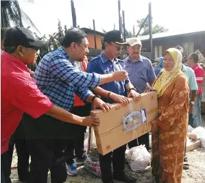  ??  ?? ZAKARIA menyampaik­an bantuan kepada mangsa kebakaran di Kampung Garinono.