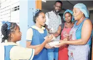  ??  ?? Two grade six students getting their lunches from members of the school’s support staff, (from left) Ricardo Dawson, Natalia Whyte and Sharon Chambers.