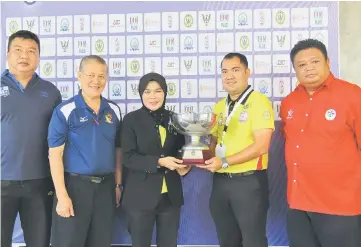  ??  ?? Normala and Mohd Fuad Mohd Sapri of Football Associatio­n of Sarawak (FAS) show the tournament’s trophy to the camera.