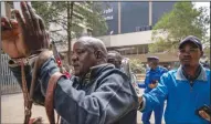  ?? ?? Pasha (left) is arrested Friday by a police officer after police used tear gas to break up a small demonstrat­ion of Maasai rights activists outside the Tanzanian high commission in downtown Nairobi.
