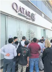  ?? AFP ?? People gather outside a branch of Qatar Airways in Abu Dhabi yesterday.