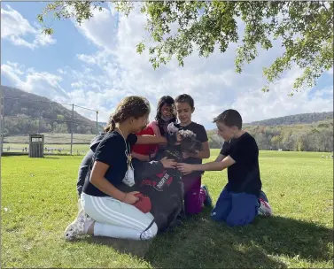  ?? CAROLYN THOMPSON — THE ASSOCIATED PRESS ?? Students from Ellicottvi­lle Central Schools in rural Ellicottvi­lle, N.Y., pet therapy dog Toby outside the school Oct. 21. Elementary school principal Maren Bush, the dog’s owner, brings Toby to school as part of the district’s efforts to improve students’ mental well-being, a focus of schools nationwide following pandemic disruption­s.