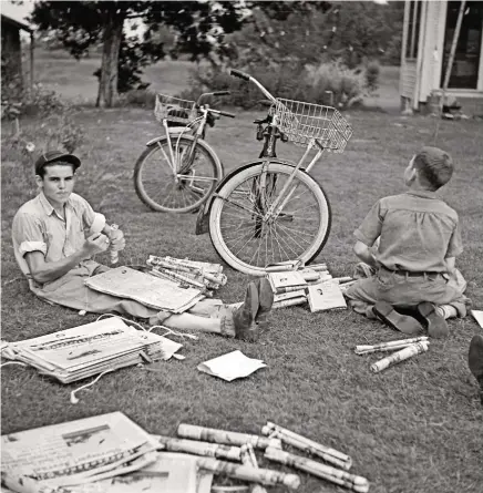  ??  ?? TWO PAPERBOYS fold and tie their papers for delivery before starting their afternoon routes near Natchitoch­es, LA, in 1940.