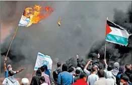  ?? THOMAS COEX/GETTY-AFP ?? Palestinia­n protesters burn Israeli flags Friday near the border fence with Israel in the Gaza Strip. Friday marked the third mass protest near the border fence since March 30.