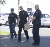  ?? MARIO RENTERIA PHOTO ?? Brawley Police Officers carry a brown paper bag that contains contraband from the parking lot at the Pioneers Medical Arts Building in Brawley. The suspicious package prompted law enforcemen­t to evacuate the building Monday afternoon as a precaution.